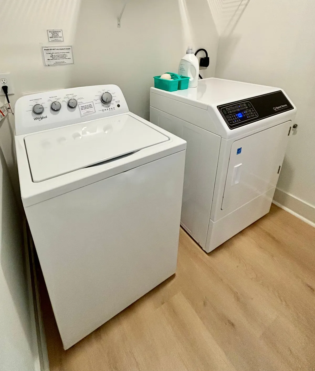 A practical laundry area featuring a washer, dryer, detergent container, and clean flooring, offering guests the convenience of in-unit laundry for longer stays.